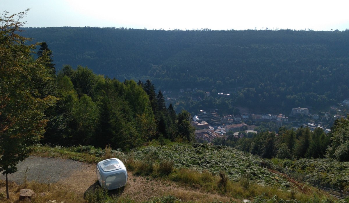 Ein kleiner Wohnwagen steht auf einem Hügel mit Blick auf ein bewaldetes Tal und eine Stadt im Hintergrund., © Nördlicher Schwarzwald