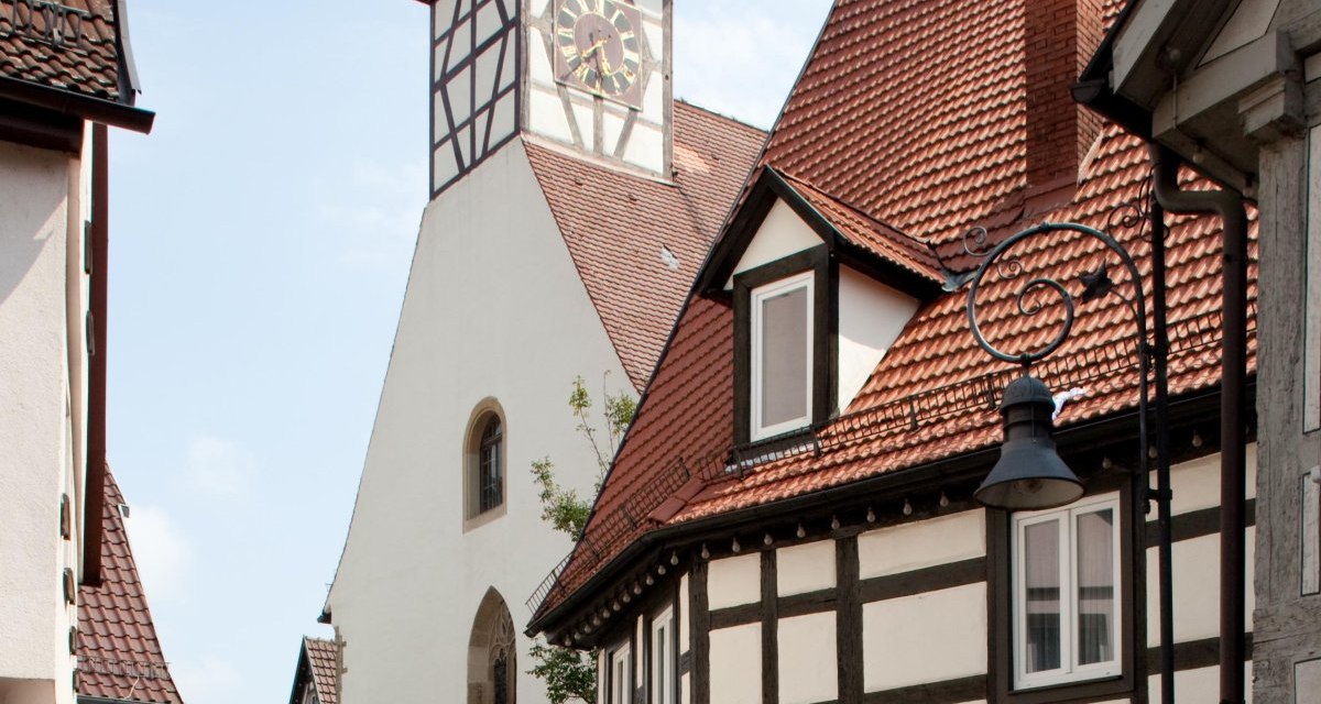 Die Nikolauskirche mit ihrem markanten Turm und umliegenden Fachwerkhäusern in einer malerischen Altstadtgasse., © Waiblingen - Stuttgart-Marketing GmbH Die Nikolauskirche mit ihrem markanten Turm und umliegenden Fachwerkhäusern in einer malerischen Altstadtgasse., © Waiblingen - Stuttgart-Marketing GmbH