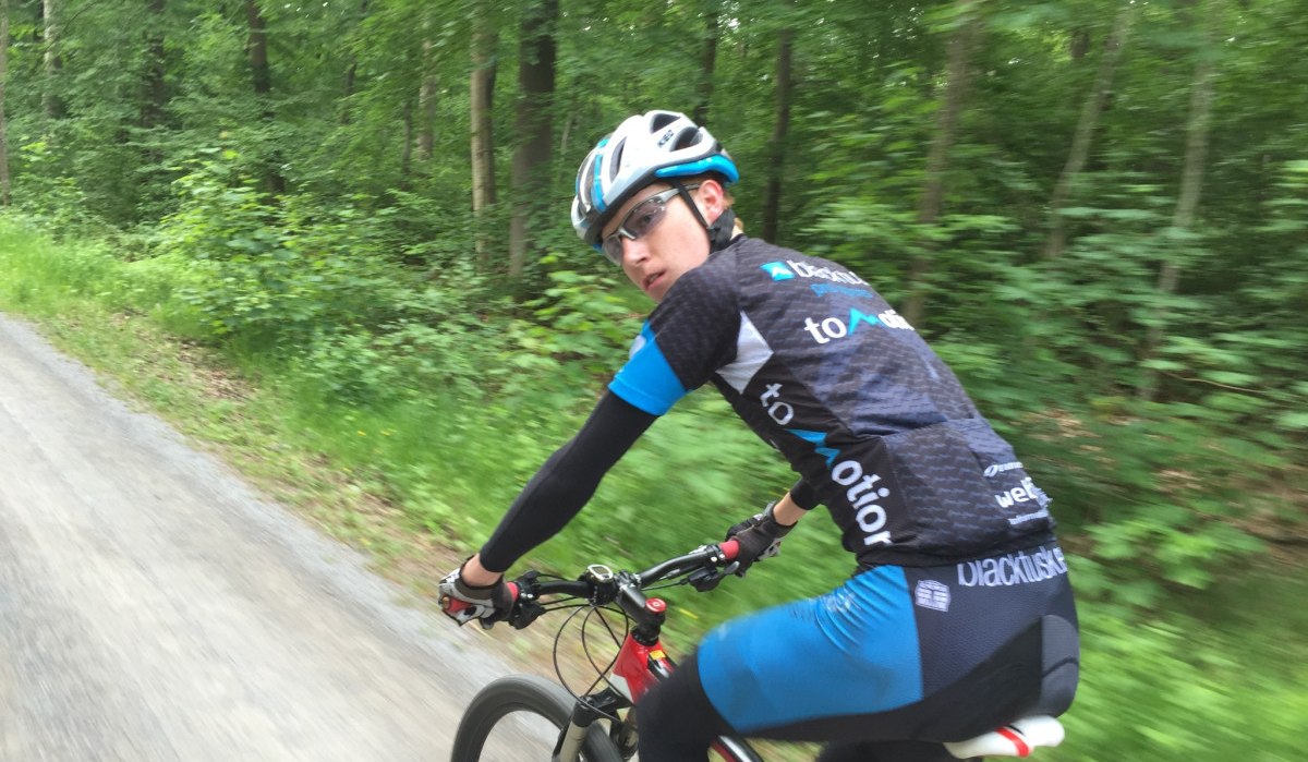 Ein Radfahrer in sportlicher Kleidung f&auml;hrt auf einem Waldweg durch einen gr&uuml;nen Wald., &copy; www.pro-cycl.de