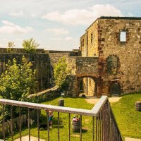 Die Ruinen der Burg Hohenrechberg in Schwäbisch Gmünd zeigen alte Steinmauern und einen grünen Innenhof mit Bäumen und Fässern., © Stuttgart-Marketing GmbH, Sarah Schmid