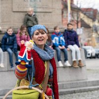 Eine Frau mit bunter Kleidung und Handpuppe steht vor einer Gruppe von Kindern, die auf einem Denkmal sitzen., &copy; Tourist Information und Ticket Service Ludwigsburg