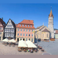 Historische Gebäude und Johanniskirche an einem sonnigen Marktplatz mit Cafés und Brunnen., © Foto Thomas Zehnder Hostrup Fotografie