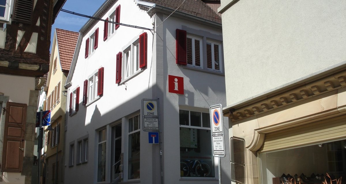 Weißes Gebäude mit roten Fensterläden und Informationsschild in einer engen Gasse. Verkehrsschilder und Schaufenster im Vordergrund., © Stadt Vaihingen an der Enz Weißes Gebäude mit roten Fensterläden und Informationsschild in einer engen Gasse. Verkehrsschilder und Schaufenster im Vordergrund., © Stadt Vaihingen an der Enz