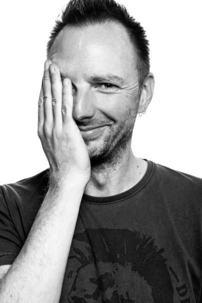 Ein Mann lächelt in die Kamera und hält eine Hand über sein Gesicht. Das Bild ist in Schwarz-Weiß gehalten., © Kulturhaus Schwanen Ein Mann lächelt in die Kamera und hält eine Hand über sein Gesicht. Das Bild ist in Schwarz-Weiß gehalten., © Kulturhaus Schwanen