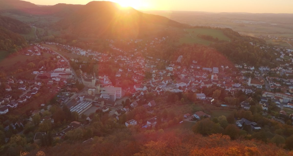 Luftaufnahme von Heubach bei Sonnenuntergang. Die Stadt liegt in einem Tal, umgeben von Hügeln. Die Sonne geht hinter den Hügeln unter, taucht die Szene in warmes Licht., © Foto: Volker Rösner Luftaufnahme von Heubach bei Sonnenuntergang. Die Stadt liegt in einem Tal, umgeben von Hügeln. Die Sonne geht hinter den Hügeln unter, taucht die Szene in warmes Licht., © Foto: Volker Rösner