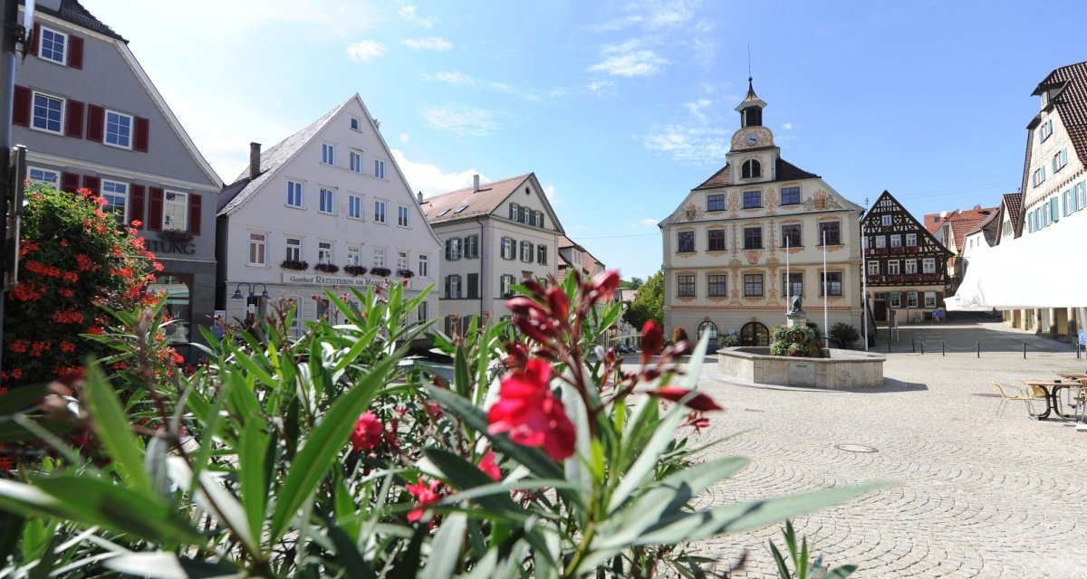 Marktplatz in Vaihingen an der Enz mit historischen Gebäuden und Blumen im Vordergrund bei sonnigem Wetter., © Stadt Vaihingen an der Enz Marktplatz in Vaihingen an der Enz mit historischen Gebäuden und Blumen im Vordergrund bei sonnigem Wetter., © Stadt Vaihingen an der Enz