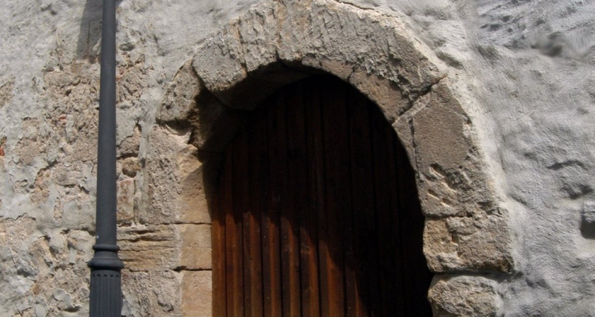Eine alte Holzt&uuml;r in einer massiven Steinmauer, daneben steht eine Stra&szlig;enlaterne. Die Mauer hat eine raue, unregelm&auml;&szlig;ige Oberfl&auml;che., &copy; Natur.Nah. Sch&ouml;nbuch & Heckeng&auml;u