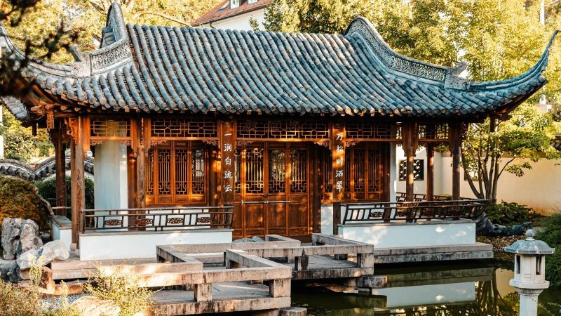 Traditionelles chinesisches Gebäude im Chinesischen Garten Stuttgart, umgeben von Bäumen und einem Teich., © Stuttgart-Marketing GmbH, Sarah Schmid