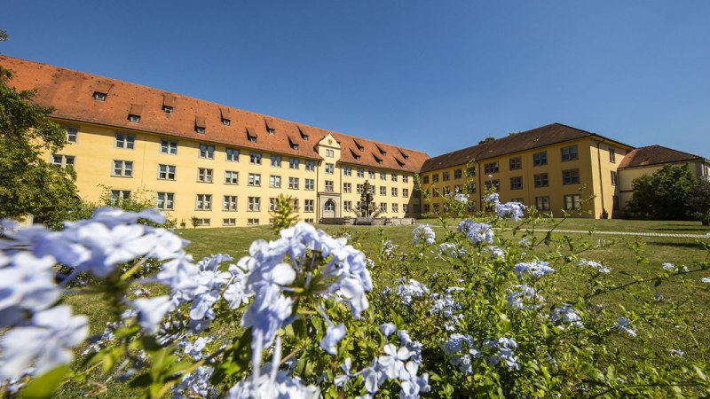 Schloss Winnental mit gelber Fassade und rotem Dach, umgeben von blühenden Blumen und grünem Rasen unter blauem Himmel., © Stuttgart-Marketing GmbH, Achim Mende