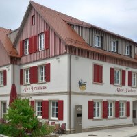 mehrst&ouml;ckiges Geb&auml;ude mit hell verputzter Fassade und r&ouml;tlich-braun holzverkleidetem Dachgeschoss, die zahlreichen wei&szlig;gerahmten Sprossenfnster haben rot lackierte Klappl&auml;den, &copy; Petra Natzkowski