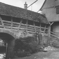 Altes Fachwerkgebäude mit Steinmauer und Holzfassaden in Waiblingen, umgeben von Fässern und Zweigen. Historische Architektur zur NS-Zeit., © WTM GmbH Waiblingen