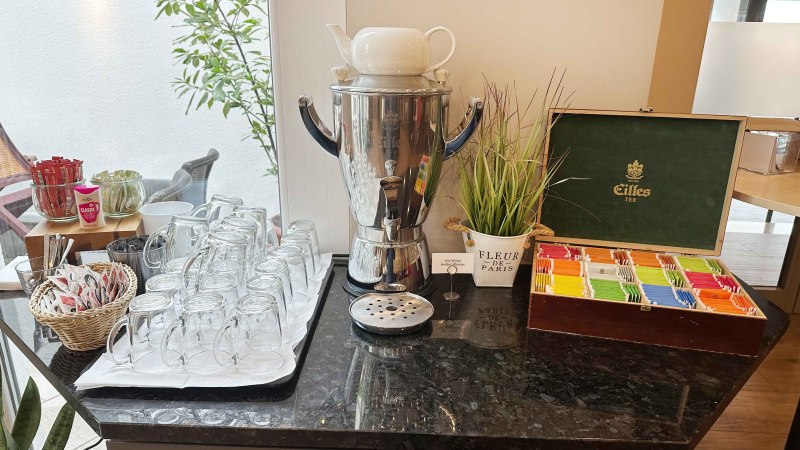 Teestation mit Gl&auml;sern, Teebeuteln und einem Wasserkocher auf einer schwarzen Theke. Dekorative Pflanze und Teebox vorhanden., &copy; Novum Hospitality