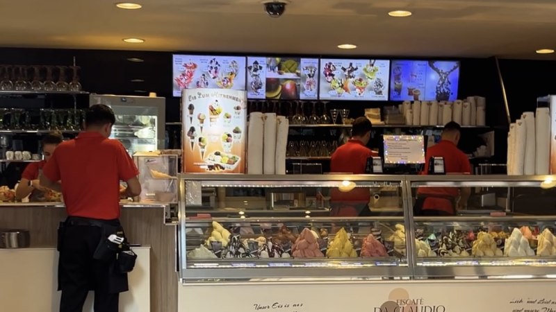 Ein Eiscaf&eacute; mit einer Theke voller bunter Eissorten. Zwei Mitarbeiter in roten Hemden bedienen Kunden. Im Hintergrund sind Men&uuml;s und Gl&auml;ser zu sehen., &copy; StadtN&uuml;rtingen