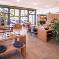 Heller Frühstücksraum mit Holztischen, Pflanzen und großen Fenstern. Gemütliche Atmosphäre mit gedeckten Tischen und Sitzkissen., © ECOINN Hotel am Campus Heller Frühstücksraum mit Holztischen, Pflanzen und großen Fenstern. Gemütliche Atmosphäre mit gedeckten Tischen und Sitzkissen., © ECOINN Hotel am Campus