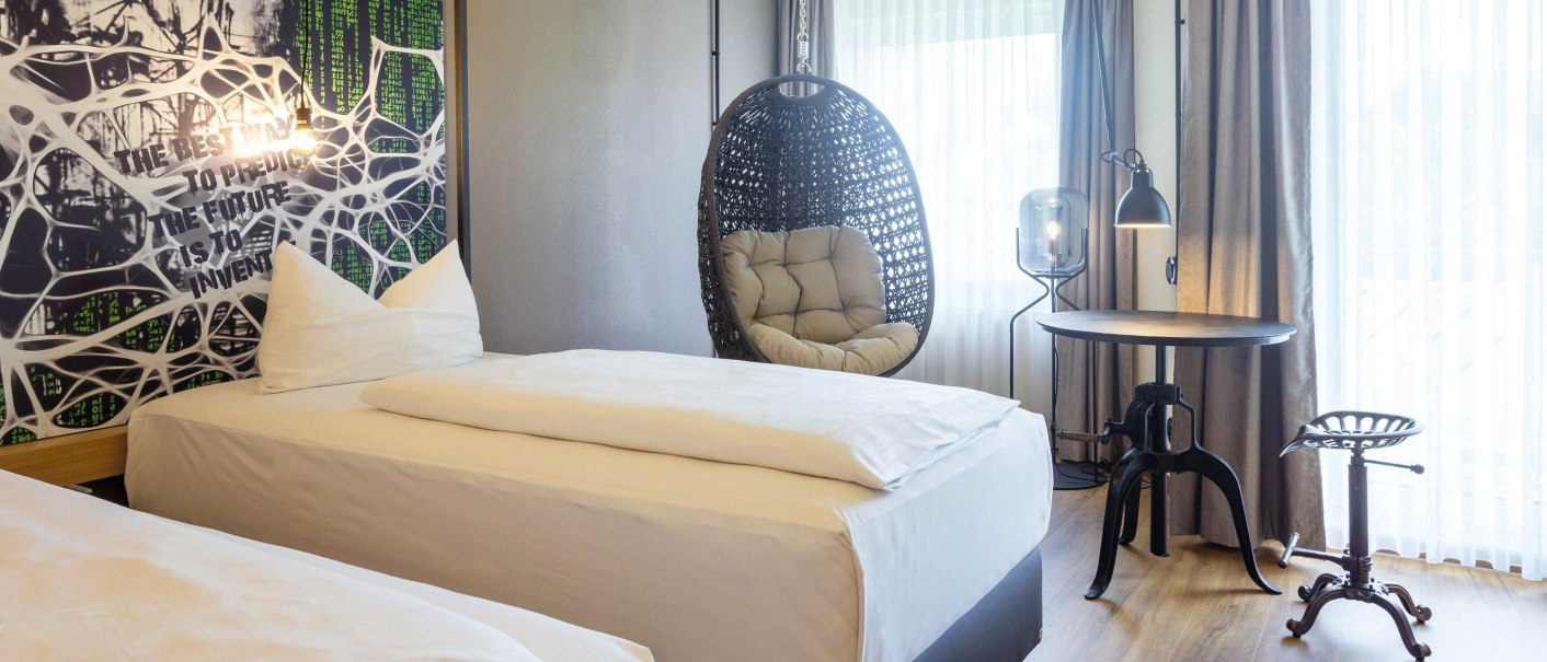 Modernes Hotelzimmer mit zwei Einzelbetten, einem Hängesessel, einem runden Tisch und einem Hocker. Große Fenster mit Vorhängen lassen viel Licht herein., © Seminaris Hotel Bad Boll Modernes Hotelzimmer mit zwei Einzelbetten, einem Hängesessel, einem runden Tisch und einem Hocker. Große Fenster mit Vorhängen lassen viel Licht herein., © Seminaris Hotel Bad Boll