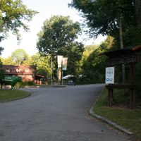 Eingang zur Weiler Hütte mit einem Schild und einer grünen Kuhfigur. Umgeben von Bäumen und einem Parkplatzschild für Gäste., © Natur.Nah. Schönbuch & Heckengäu