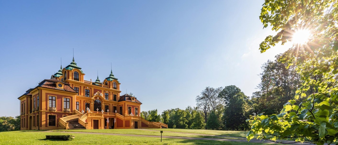 Schloss Favorite in Ludwigsburg, umgeben von gr&uuml;nen B&auml;umen und strahlendem Sonnenschein. Die barocke Architektur hebt sich vor dem blauen Himmel ab., &copy; &copy; Stuttgart-Marketing GmbH, Werner Dieterich