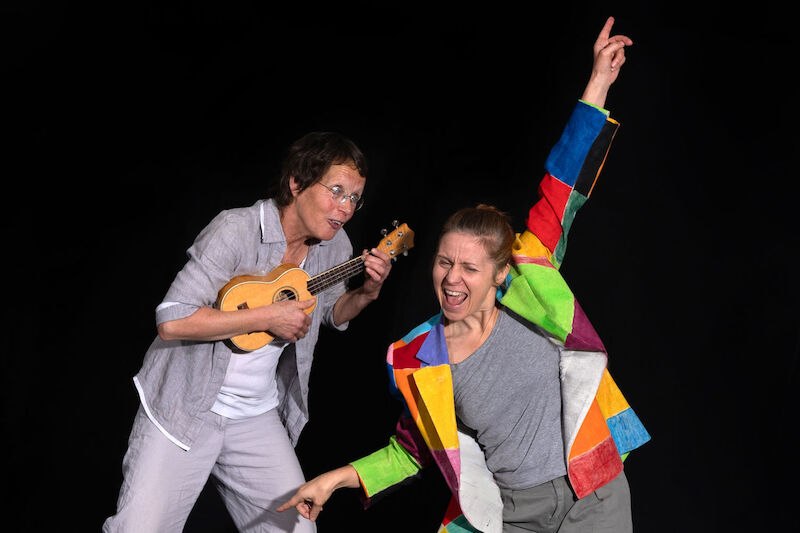 Zwei Personen auf einer Bühne. Eine spielt Ukulele, die andere trägt eine bunte Jacke und tanzt begeistert., © Stadt Winnenden Zwei Personen auf einer Bühne. Eine spielt Ukulele, die andere trägt eine bunte Jacke und tanzt begeistert., © Stadt Winnenden