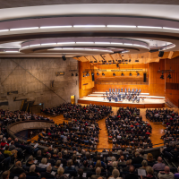Ein großer Konzertsaal mit modernem Design, gefüllt mit Zuschauern. Auf der Bühne spielt ein Orchester. Die Architektur ist beeindruckend., © Holger Schneider Ein großer Konzertsaal mit modernem Design, gefüllt mit Zuschauern. Auf der Bühne spielt ein Orchester. Die Architektur ist beeindruckend., © Holger Schneider