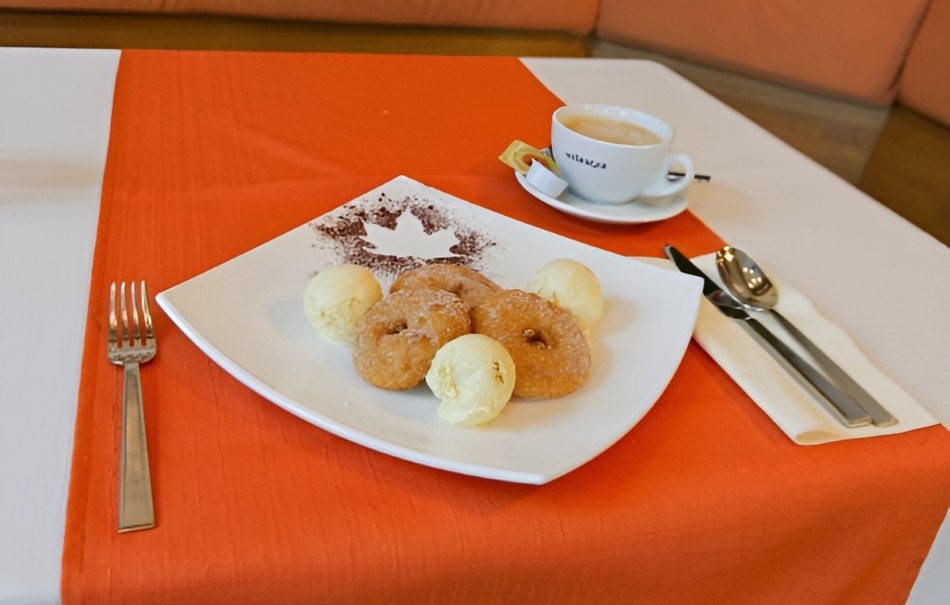Teller mit Donuts und Eis auf roter Tischdecke, daneben Kaffee und Besteck., © Hotel Neuwirtshaus Teller mit Donuts und Eis auf roter Tischdecke, daneben Kaffee und Besteck., © Hotel Neuwirtshaus