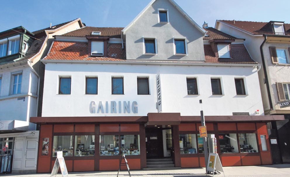 Fassade eines zweistöckigen Gebäudes mit dem Schriftzug 'GAIRING' über dem Eingang. Große Fenster im Erdgeschoss, Dachfenster im Obergeschoss., © City Marketing Nürtingen Fassade eines zweistöckigen Gebäudes mit dem Schriftzug 'GAIRING' über dem Eingang. Große Fenster im Erdgeschoss, Dachfenster im Obergeschoss., © City Marketing Nürtingen