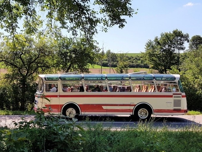 Ein nostalgischer Oldtimerbus fährt durch die grüne Landschaft der Schwäbischen Alb. Der Himmel ist klar und sonnig., © SwabianTravel Ein nostalgischer Oldtimerbus fährt durch die grüne Landschaft der Schwäbischen Alb. Der Himmel ist klar und sonnig., © SwabianTravel
