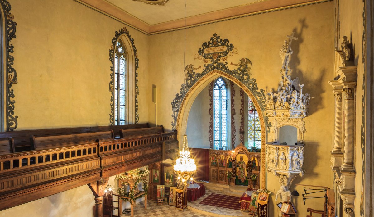 Innenansicht der Michaelskirche mit reich verziertem Altar, Kanzel und bemalter Decke. Holzbänke und Stühle sind im Raum verteilt., © Remstal Tourismus e.V.
