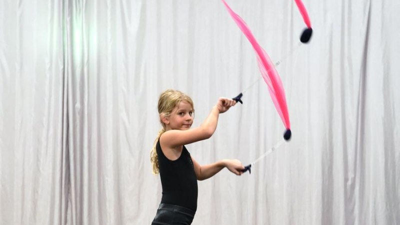 Ein Kind jongliert mit pinken T&uuml;chern vor einem grauen Vorhang. Es tr&auml;gt ein schwarzes Outfit und wirkt konzentriert., &copy; Kunstschule Labyrinth