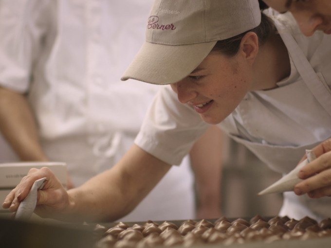 Eine Person in einer B&auml;ckerei verziert Pralinen mit einem Spritzbeutel. Sie tr&auml;gt eine Schirmm&uuml;tze und ein wei&szlig;es T-Shirt., &copy; Stadt G&ouml;ppingen