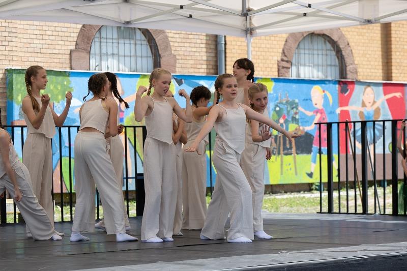Kinder in beigen Outfits tanzen auf einer Bühne vor einer bunten Wandmalerei. Sie sind Teil eines Ferienworkshops in Ludwigsburg., © Kunstschule Labyrinth