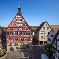 Fachwerk-Rathaus in Großbottwar, umgeben von historischen Gebäuden. Der Platz ist mit Blumen geschmückt, der Himmel ist klar und blau., © Stuttgart Marketing Mende Fachwerk-Rathaus in Großbottwar, umgeben von historischen Gebäuden. Der Platz ist mit Blumen geschmückt, der Himmel ist klar und blau., © Stuttgart Marketing Mende