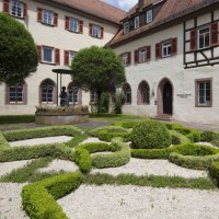 Ein gepflegter Garten mit kunstvollen Heckenmustern vor einem historischen Geb&auml;ude mit Fachwerk und roten Fensterl&auml;den., &copy; Stadtverwaltung Weil der Stadt