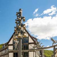 Skulptur mit Glocken und Figuren auf dem Marktplatz von Bad Urach, umgeben von Fachwerkhäusern und blauem Himmel., © Stuttgart-Marketing GmbH, Sarah Schmid