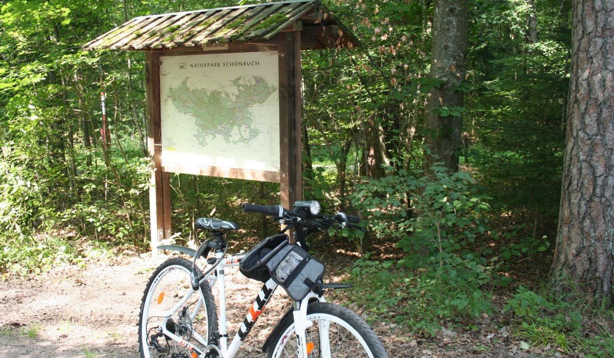 Ein Fahrrad steht vor einer Infotafel mit Karte des Naturparks Schönbuch, umgeben von dichtem Wald., © Natur.Nah. Schönbuch & Heckengäu