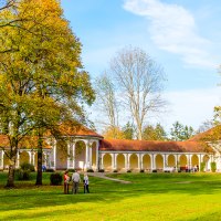 Herbstlicher Kurpark Bad Boll mit gelb-orange gefärbten Bäumen und einem historischen Gebäude mit Arkaden im Hintergrund., © Bad Boll