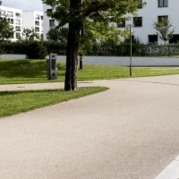 Ein gepflegter Park mit geschwungenen Gehwegen, Bäumen und modernen Wohngebäuden im Hintergrund. Ein Gedenkstein ist sichtbar., © Foto-Kunst Andreas Keller Ein gepflegter Park mit geschwungenen Gehwegen, Bäumen und modernen Wohngebäuden im Hintergrund. Ein Gedenkstein ist sichtbar., © Foto-Kunst Andreas Keller