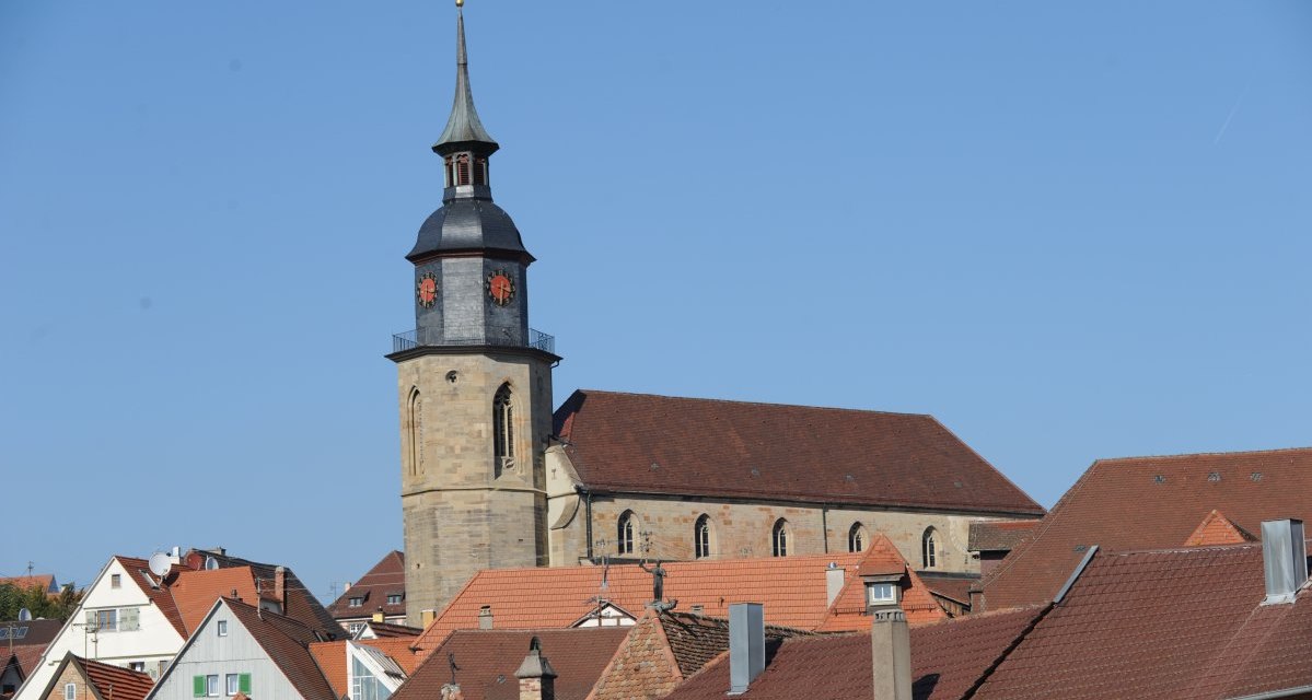 Kirchturm mit Uhr über roten Dächern, blauer Himmel im Hintergrund., © Land der 1000 Hügel - Kraichgau-Stromberg Kirchturm mit Uhr über roten Dächern, blauer Himmel im Hintergrund., © Land der 1000 Hügel - Kraichgau-Stromberg