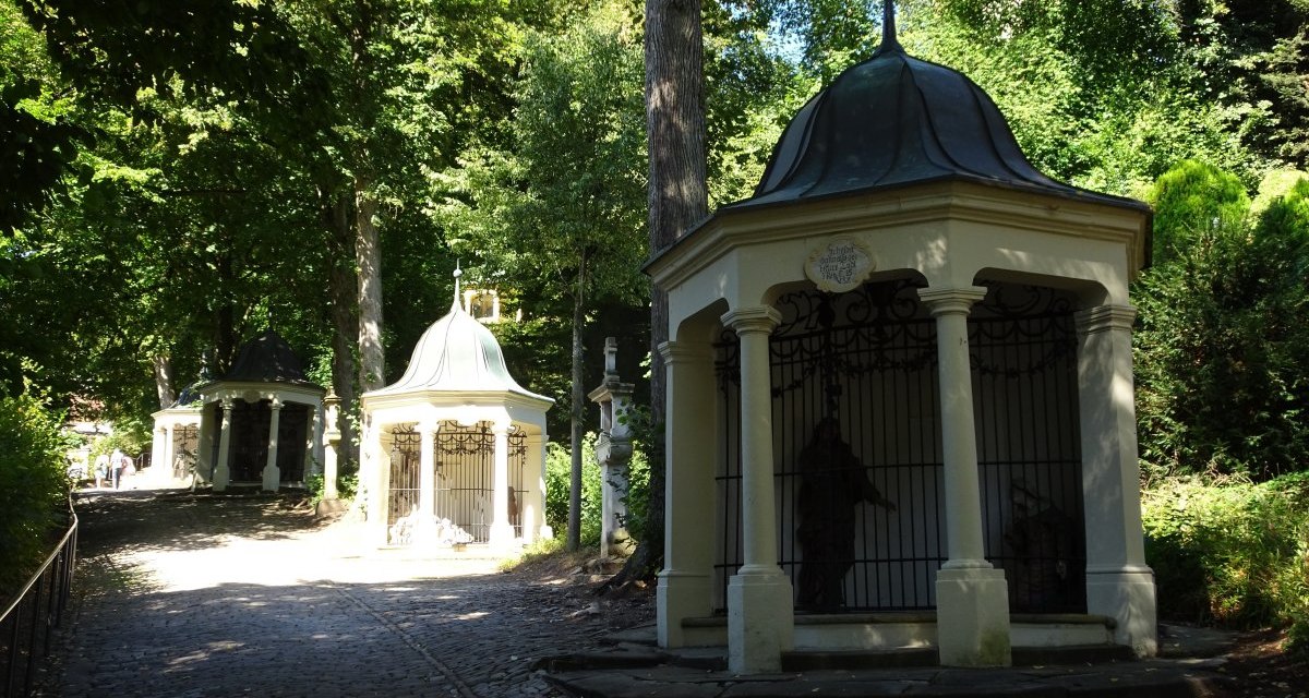 Stationen des Kreuzweges hinauf zur Felsenkapelle St. Salvator umrahmt von grünen Bäumen., © Foto: Cornelia Steinbach Stationen des Kreuzweges hinauf zur Felsenkapelle St. Salvator umrahmt von grünen Bäumen., © Foto: Cornelia Steinbach