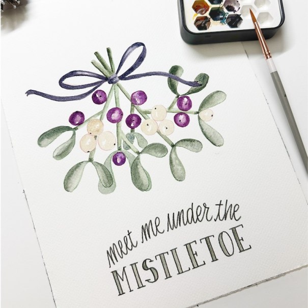 Aquarellbild von Mistelzweigen mit handgeschriebenem Text 'meet me under the mistletoe'. Daneben ein Pinsel und eine Farbpalette., &copy; Mercedes-Benz AG