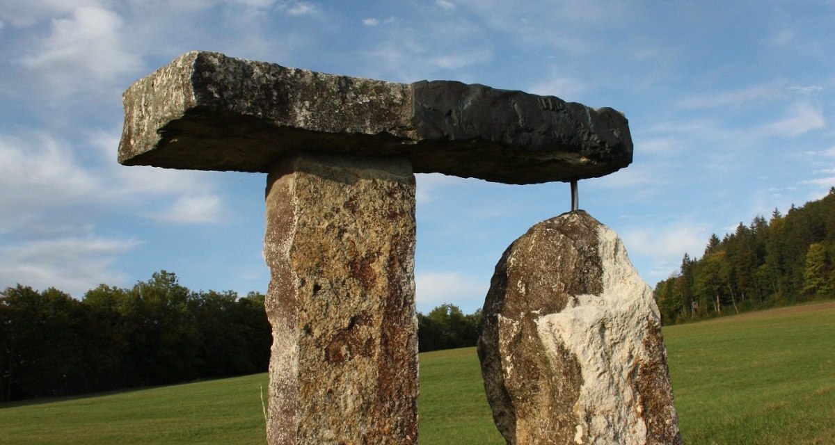 Eine Steinskulptur aus drei großen Steinen steht auf einer grünen Wiese unter einem blauen Himmel mit Wolken., © Touristik und Marketing GmbH Eine Steinskulptur aus drei großen Steinen steht auf einer grünen Wiese unter einem blauen Himmel mit Wolken., © Touristik und Marketing GmbH