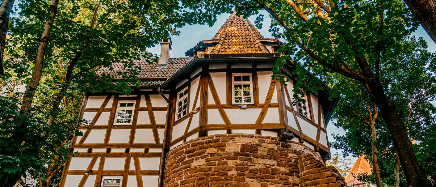 Fachwerkhaus mit rundem Turm, umgeben von Bäumen. Der Turm hat ein spitzes Dach, das Gebäude ist aus Holz und Stein gebaut., © Stuttgart-Marketing GmbH, Thomas Niedermüller