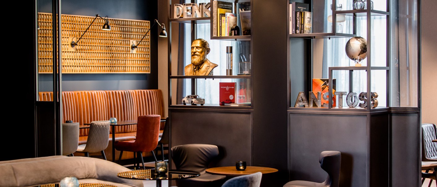 Moderne Lounge mit gemütlichen Sitzgelegenheiten, Bücherregalen und Dekorationen wie einer Büste und einem Globus. Elegantes, stilvolles Ambiente., © TOMAS Moderne Lounge mit gemütlichen Sitzgelegenheiten, Bücherregalen und Dekorationen wie einer Büste und einem Globus. Elegantes, stilvolles Ambiente., © TOMAS