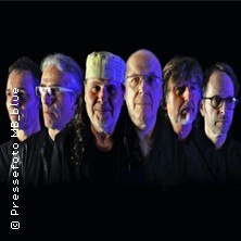 Sechs Männer stehen nebeneinander vor einem schwarzen Hintergrund, beleuchtet in blauem und violettem Licht., © links im Bild Sechs Männer stehen nebeneinander vor einem schwarzen Hintergrund, beleuchtet in blauem und violettem Licht., © links im Bild