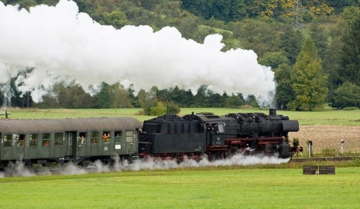 Eine historische Dampflok der Schwäbischen Waldbahn zieht Waggons durch eine grüne Landschaft, umgeben von Bäumen und Feldern., © Aktiv-Region Stuttgart Eine historische Dampflok der Schwäbischen Waldbahn zieht Waggons durch eine grüne Landschaft, umgeben von Bäumen und Feldern., © Aktiv-Region Stuttgart