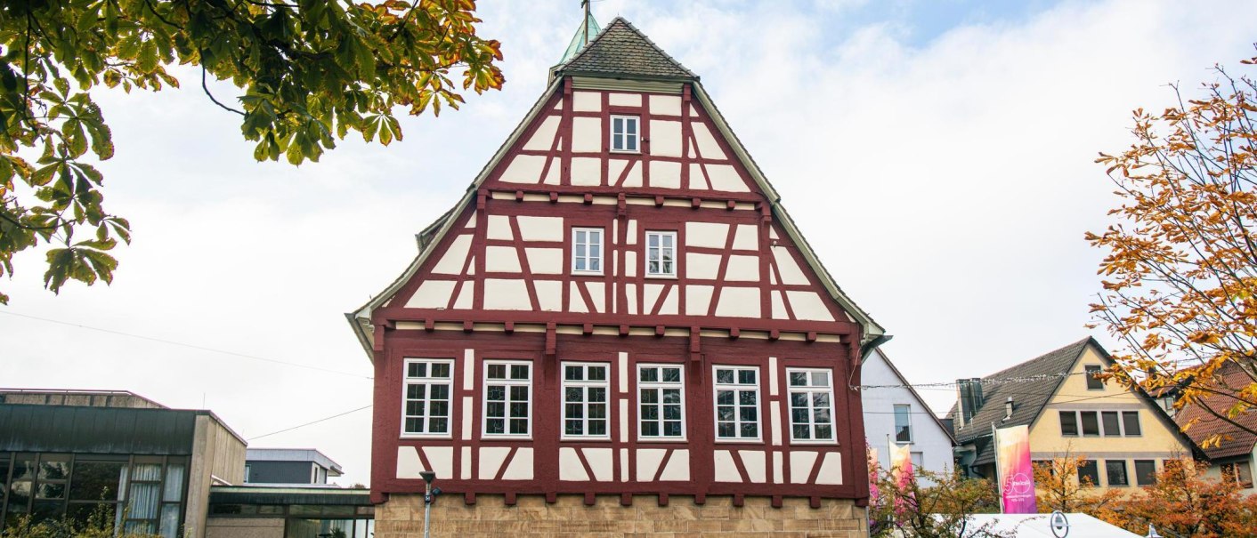 Ein traditionelles Fachwerkhaus in der Innenstadt von Echterdingen, umgeben von herbstlichen Bäumen und moderner Architektur., © Stuttgart-Marketing GmbH, Sarah Schmid