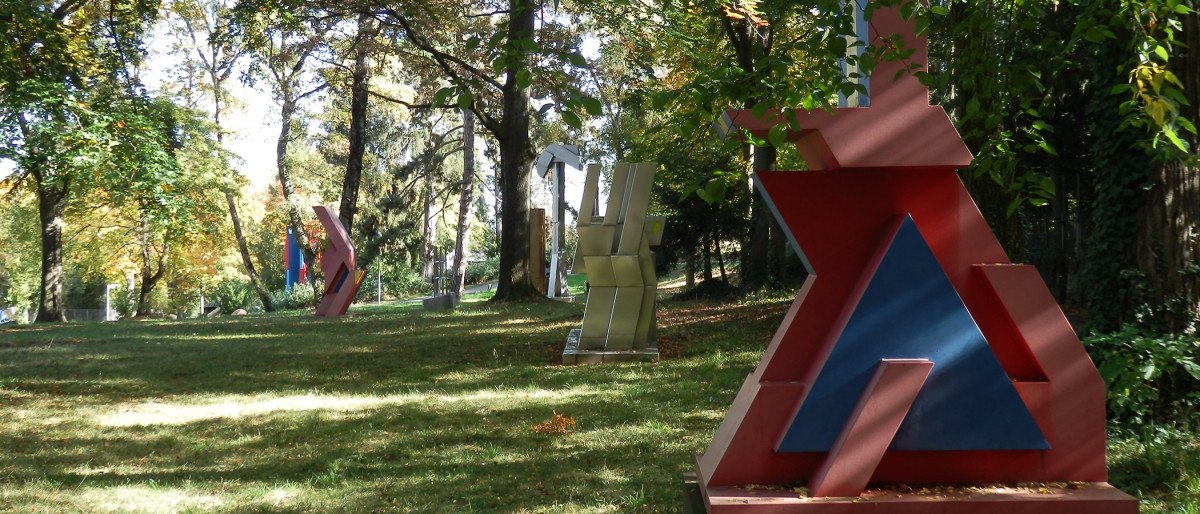 Moderne geometrische Skulpturen in einem grünen Park mit Bäumen und Rasenfläche, beleuchtet von Sonnenlicht., © Stuttgart-Marketing GmbH Moderne geometrische Skulpturen in einem grünen Park mit Bäumen und Rasenfläche, beleuchtet von Sonnenlicht., © Stuttgart-Marketing GmbH