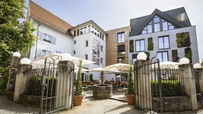 Hotel-Restaurant Schwanen mit moderner Fassade, Terrasse mit Sonnenschirmen und dekorativen Pflanzen. Historisches Tor im Vordergrund., © Hotel-Restaurant Schwanen Hotel-Restaurant Schwanen mit moderner Fassade, Terrasse mit Sonnenschirmen und dekorativen Pflanzen. Historisches Tor im Vordergrund., © Hotel-Restaurant Schwanen