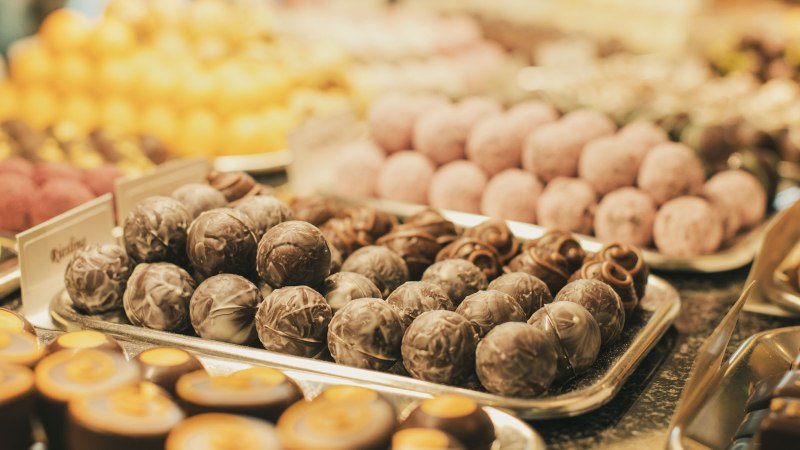 Eine Auswahl an Pralinen und Marzipan in verschiedenen Farben und Formen auf Tabletts präsentiert., © Frischmann-Marzipan-GmbH Eine Auswahl an Pralinen und Marzipan in verschiedenen Farben und Formen auf Tabletts präsentiert., © Frischmann-Marzipan-GmbH