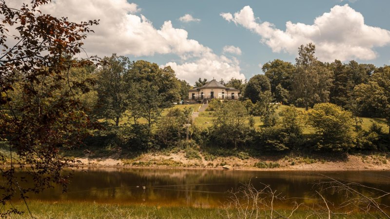 Das Bärenschlössle thront auf einem grünen Hügel am Bärensee, umgeben von üppigen Bäumen und einem klaren Himmel mit weißen Wolken., © SMG, Sarah Schmid Das Bärenschlössle thront auf einem grünen Hügel am Bärensee, umgeben von üppigen Bäumen und einem klaren Himmel mit weißen Wolken., © SMG, Sarah Schmid