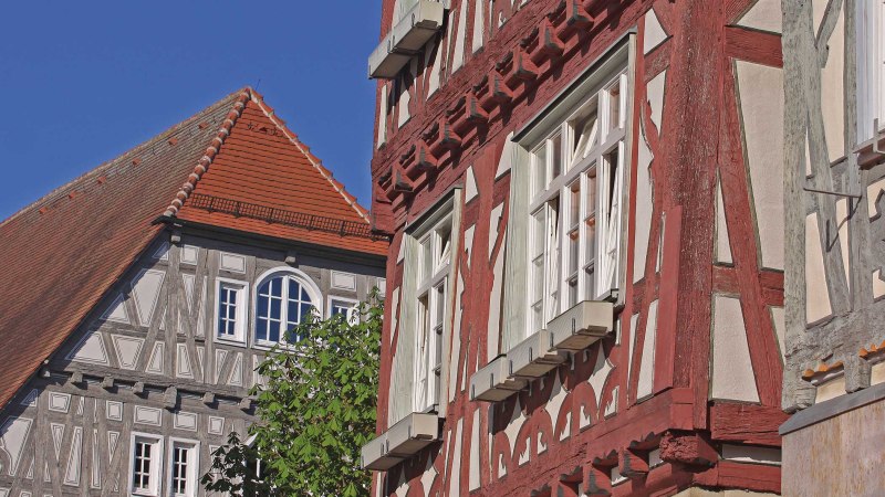 Fachwerkh&auml;user mit roten und grauen Balken, wei&szlig;e Fenster und ein rotes Ziegeldach vor klarem, blauem Himmel., &copy; Stadt Vaihingen an der Enz